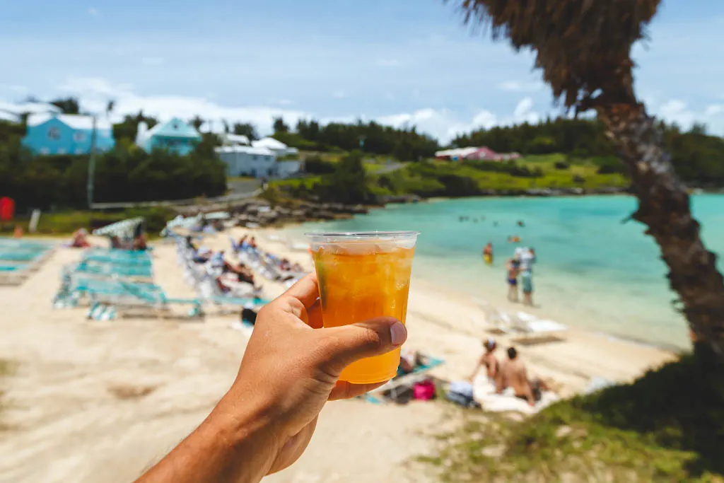 Holding a delicious dark and stormy cocktail in front of Tabacco Bay in Bermuda.