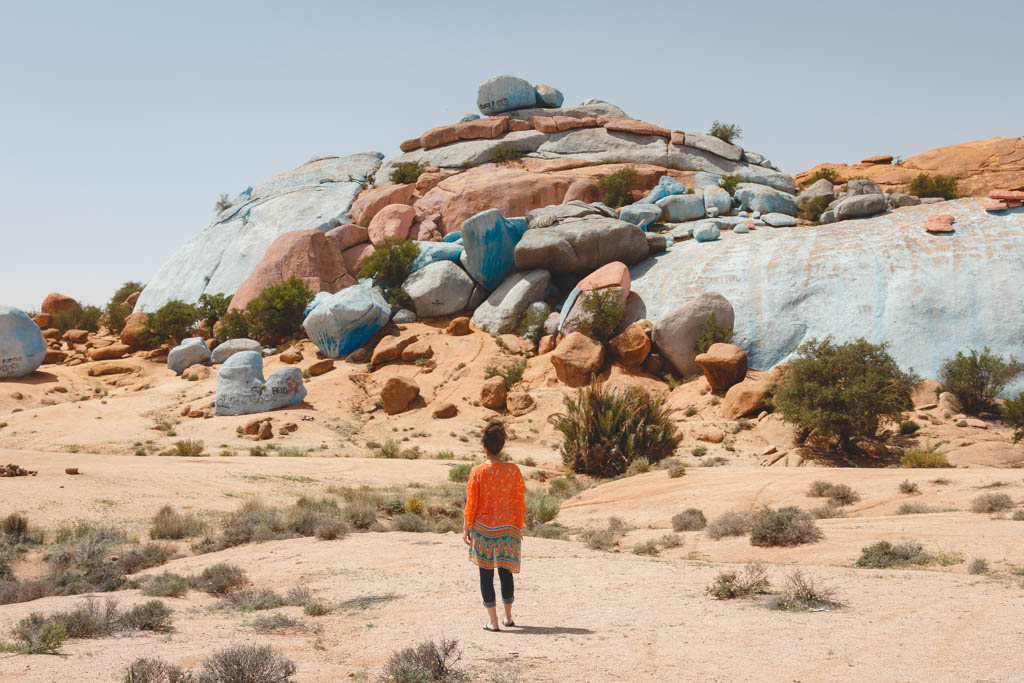 Nina standing in awe at the giant painted rocks in Morocco.