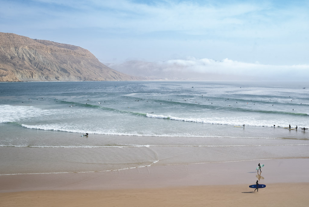 Expanse beach with surfers riding long waves in Imsouane.