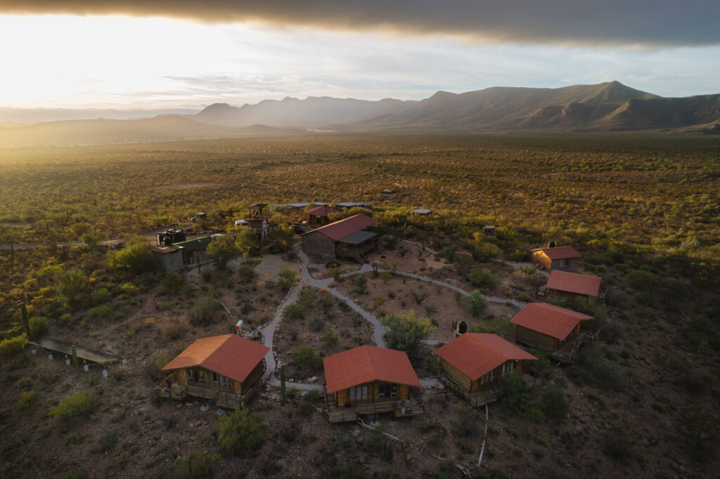 Aerial view over the Tres Virgenes Eco Resort cabins at sunset.