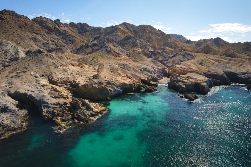 Aerial view of Playa los Arquitos nestled in the mountains and cliffs of Baja California Sur.