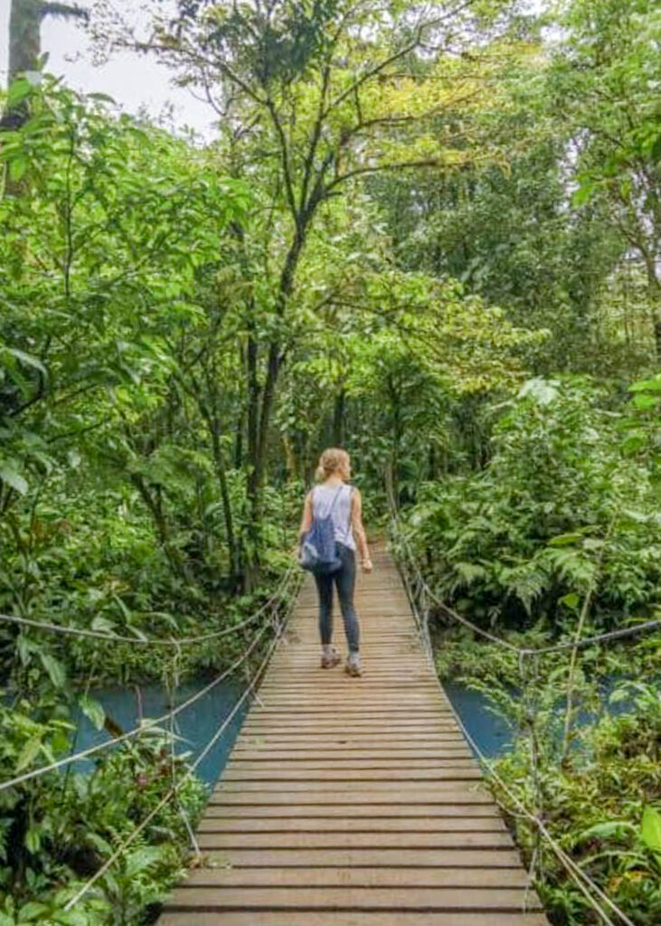 Woman crossing a suspension bridge in the forest.
