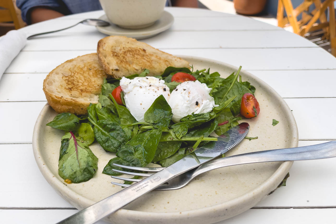 A beautifully arranged plate of sourdough toast, spinach salad and two perfectly poached eggs on top at the restaurant Miscelanea. 