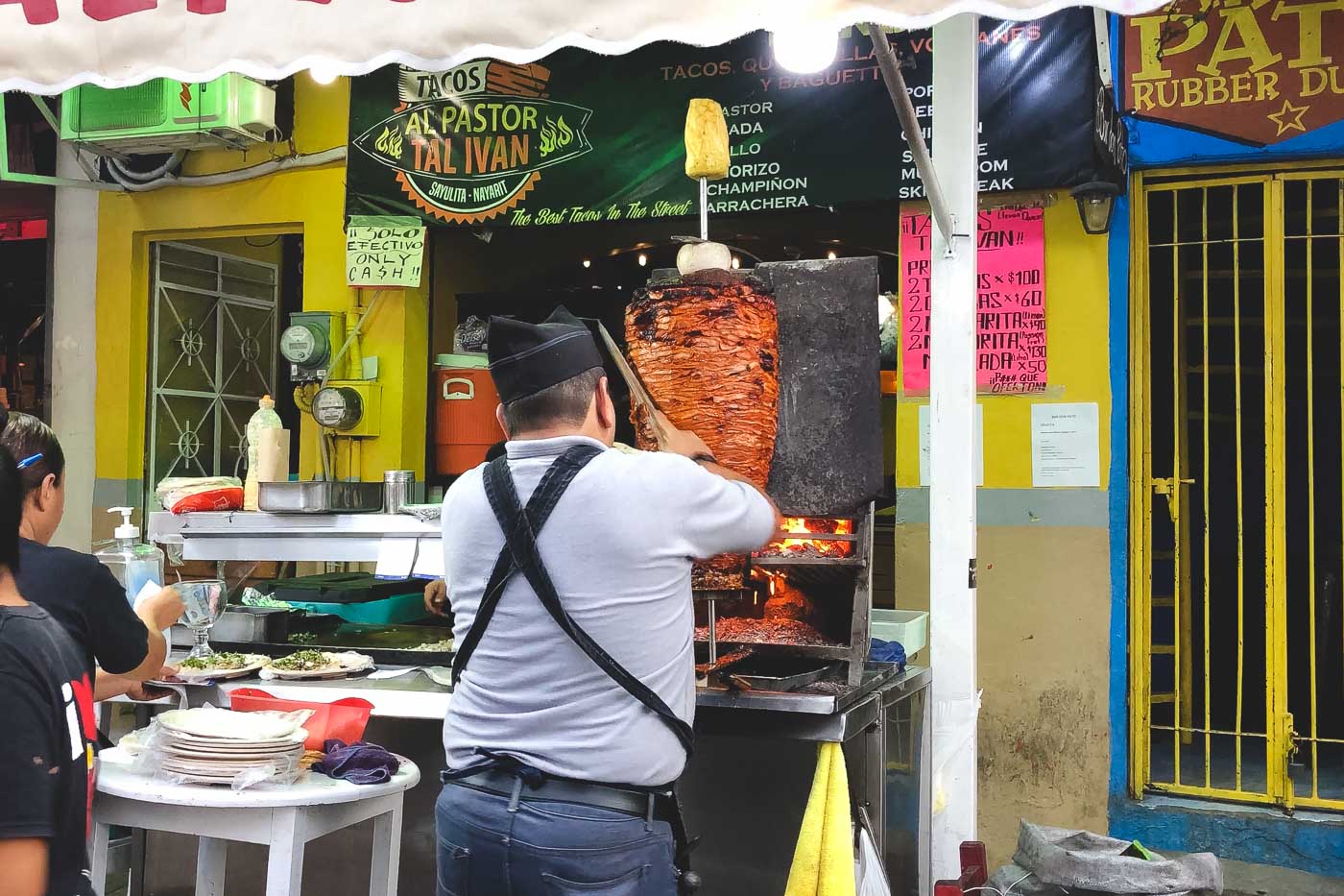 A rotisserie of Al Pastor meat being shaved with a machete by the cook at Tal Ivan restaurant at the main square of Sayulita.