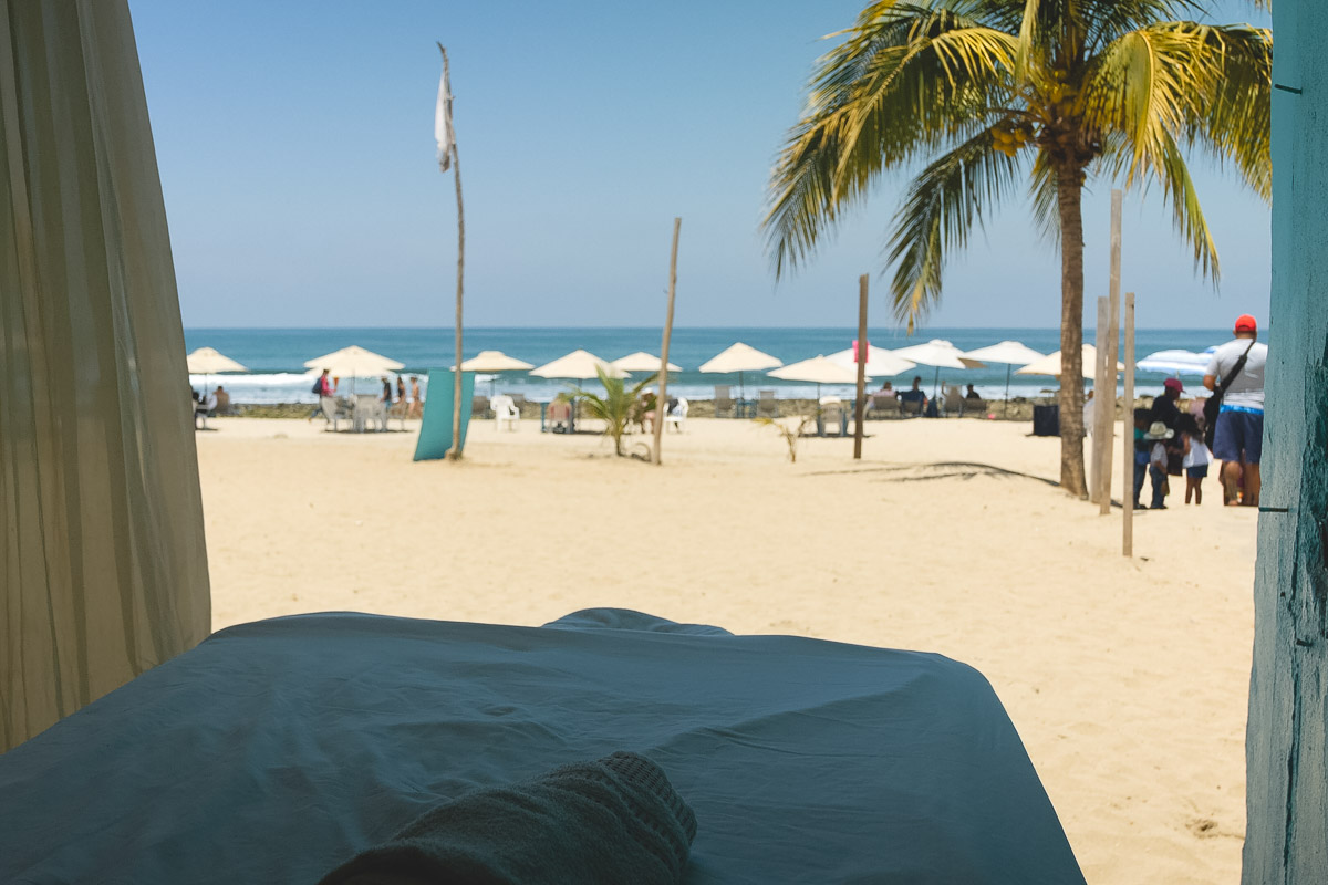 Massage bed on the beach with a palm tree.
