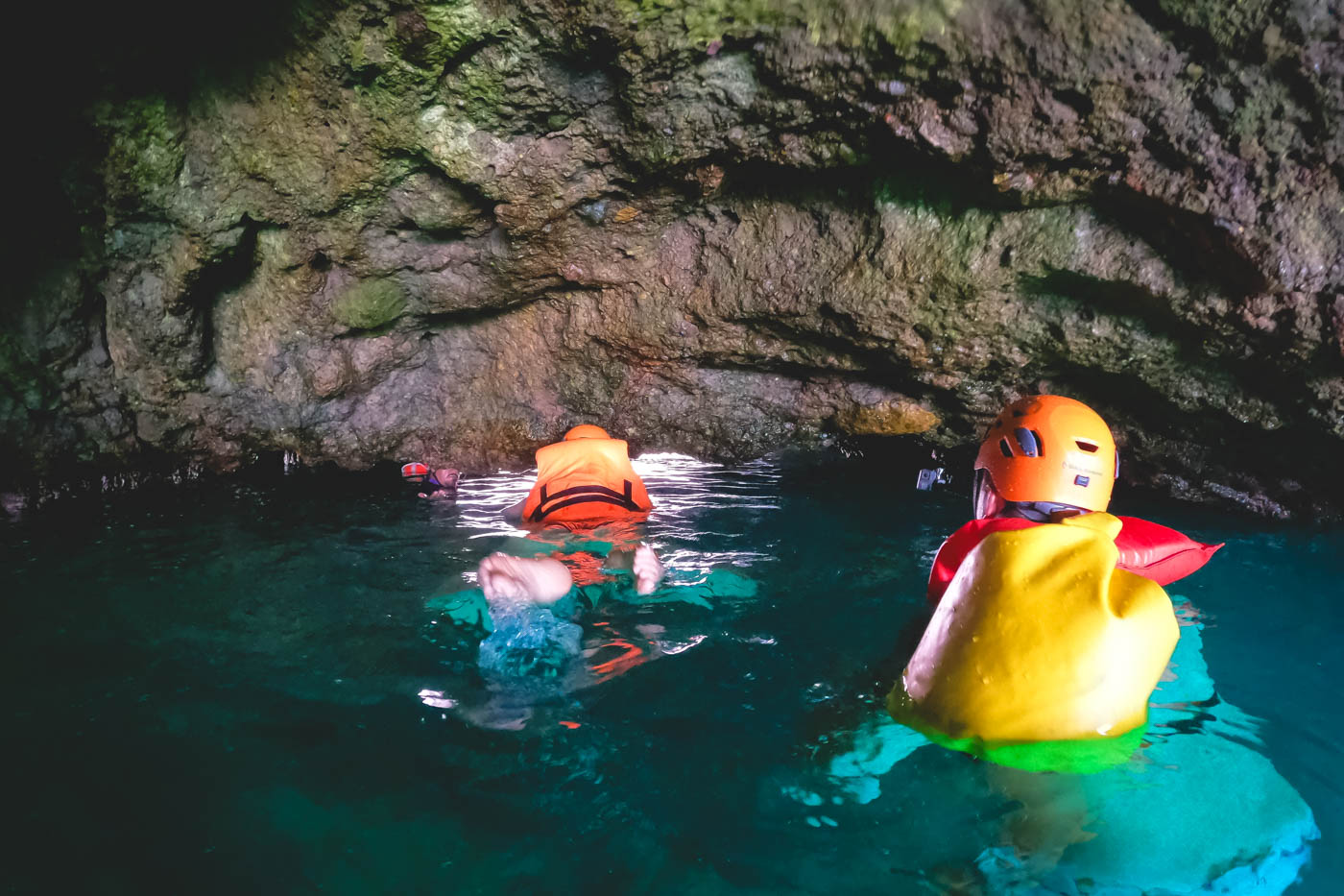 People equipped with lifejackets swimming through the cave to get to Hidden beach.