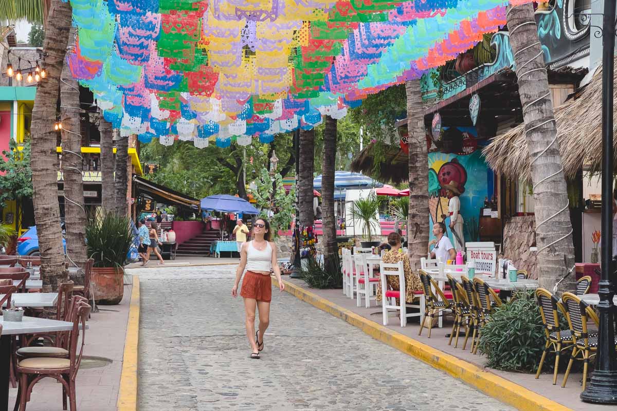 Me walking down a main street Sayulita with colorful mexican papel picado above.