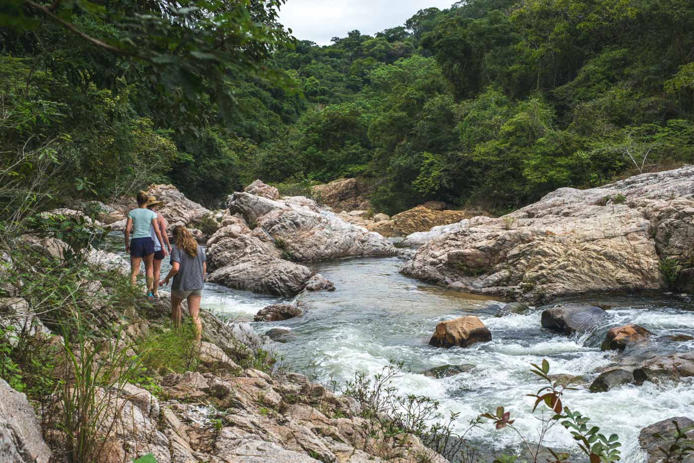 Tourists hiking alongside the river that leads to Yelapa Waterfall 2 in the forest.