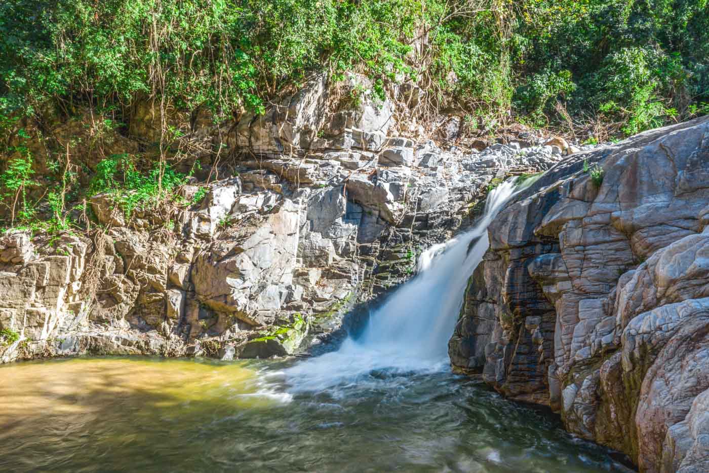 A long exposure of Yelapa Waterfall 2 in between rocks on a sunny day.