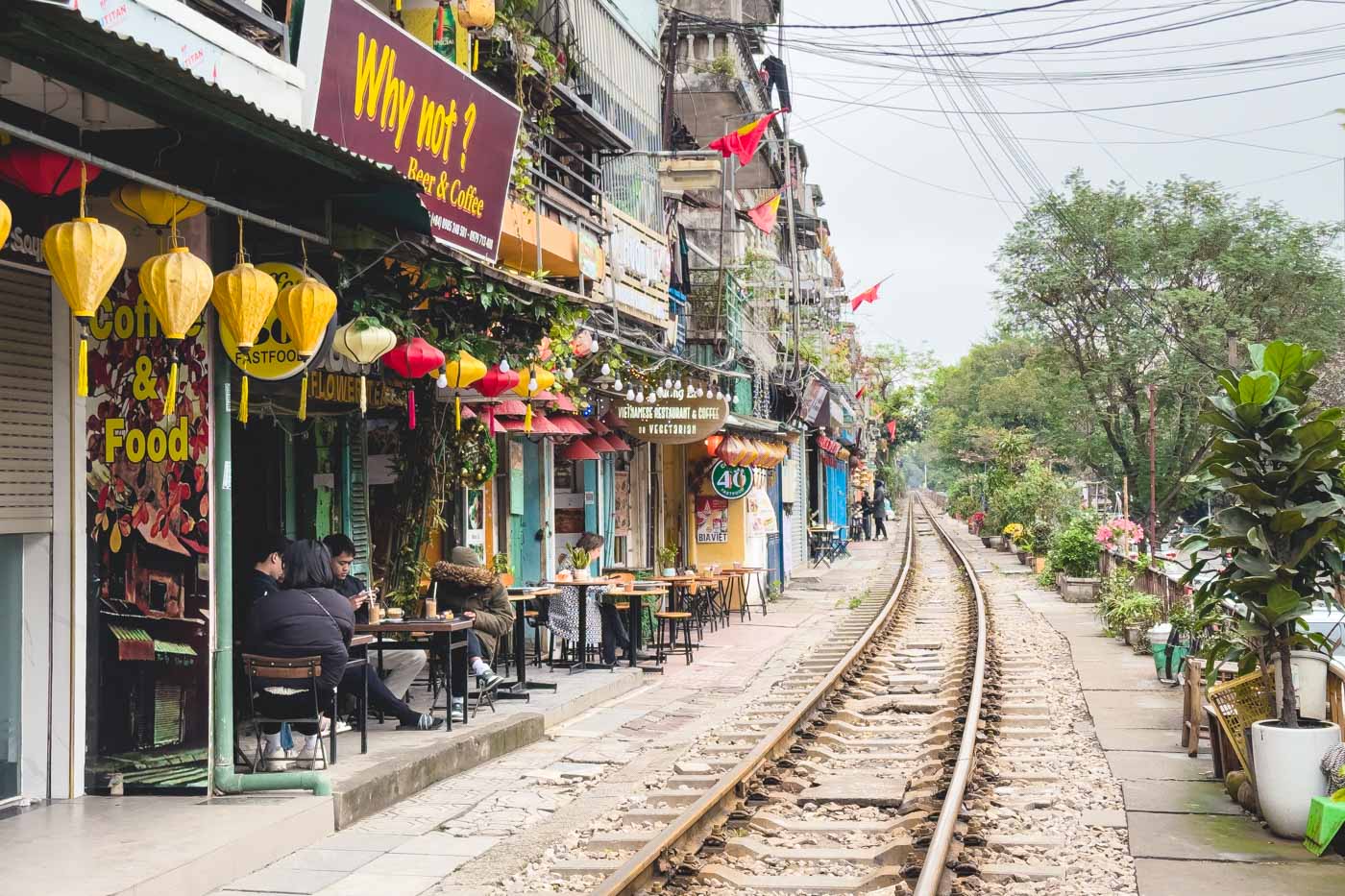 People sitting in cafes lined along the railway track of Hanoi Train Street.