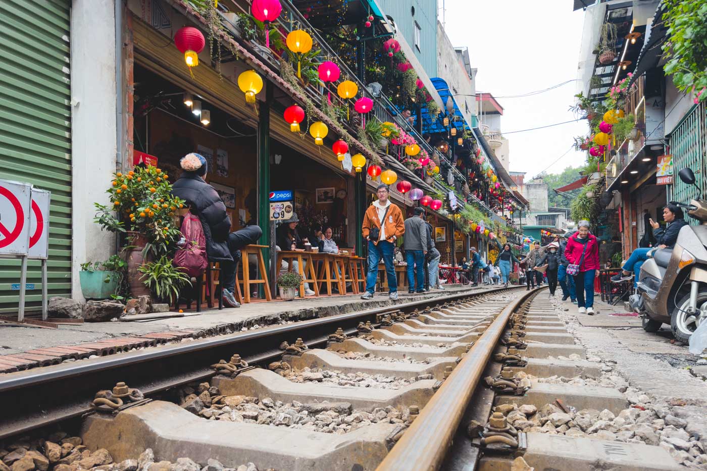 Low angle of the train tracks at Hanoi Train Street while people walk up and down them.