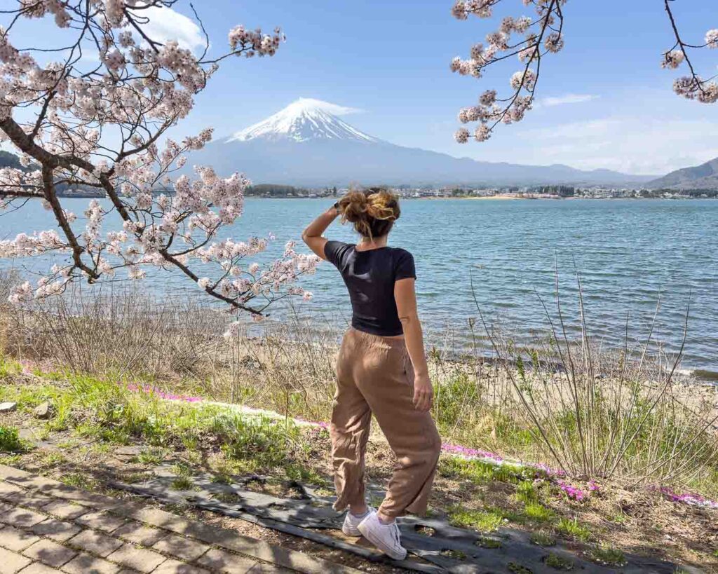 Nina at Kogamasao Memorial Park with cherry blossom, a lake and Mount Fuji in the back.