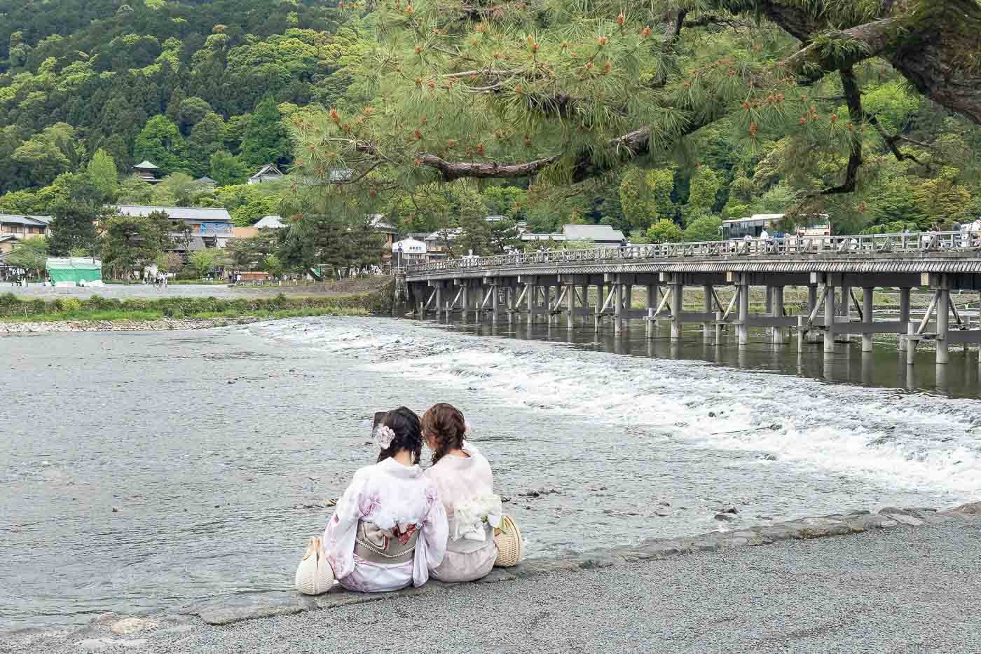 Two women in Arashiyama Kyoto along a river.