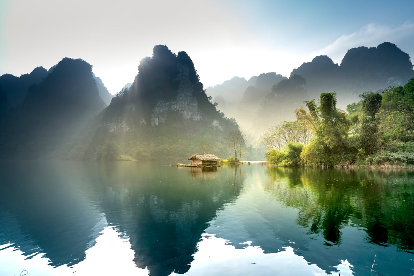 Stunning sunrise over a peaceful lake surrounded by lush mountains in Thượng Lâm, Vietnam.