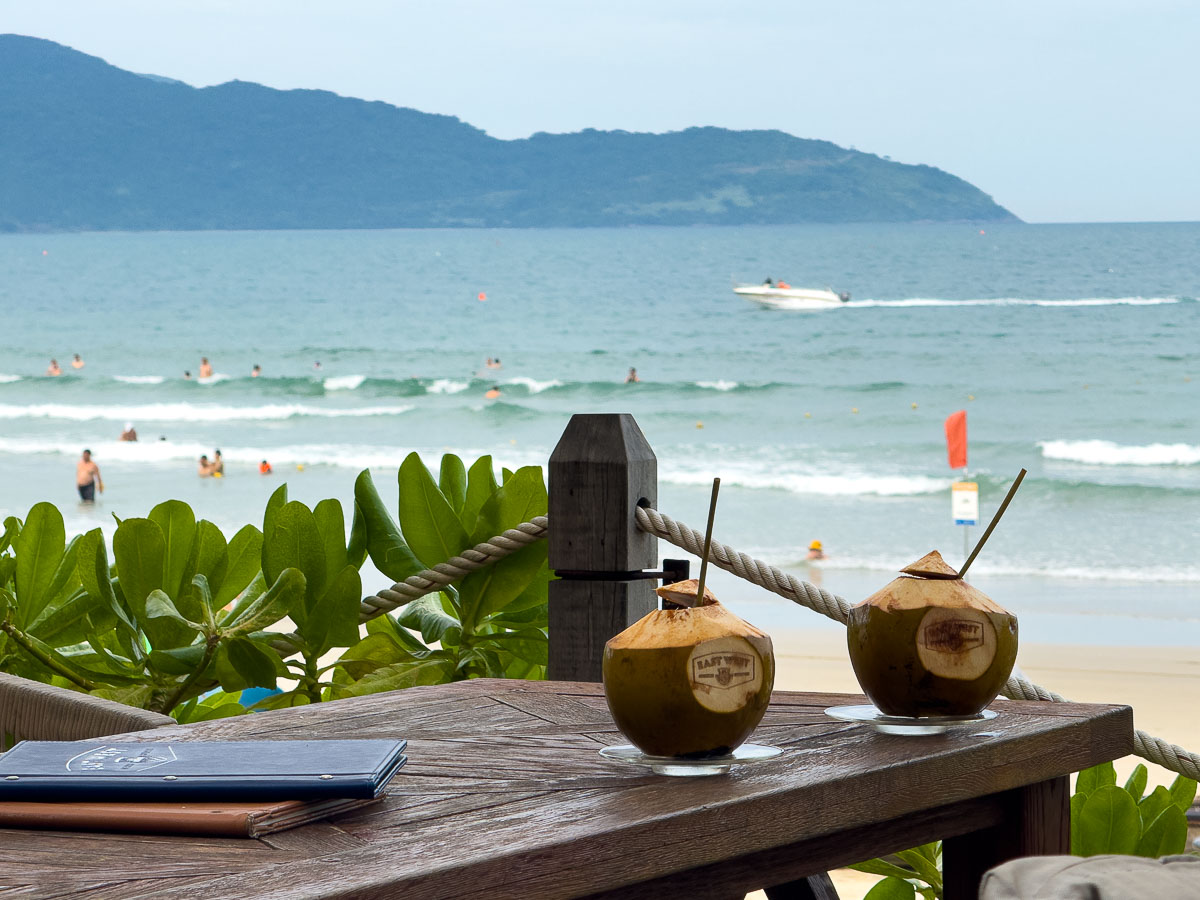 Two coconuts on a table with a beach background.