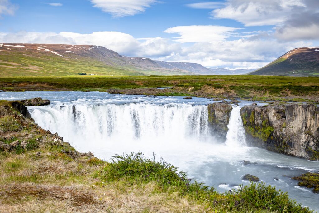 Breathtaking view of a powerful waterfall in Akureyri, Iceland with lush green surroundings.