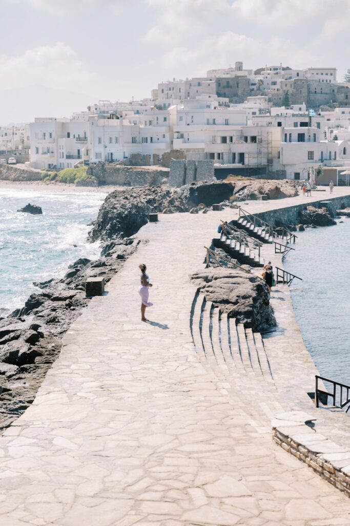 a woman walking down a path next to the ocean