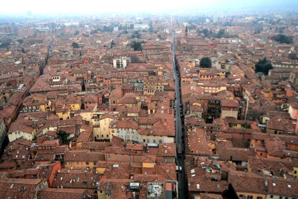 Aerial shot of Bologna, Italy showcasing its historic red rooftops and medieval architecture.
