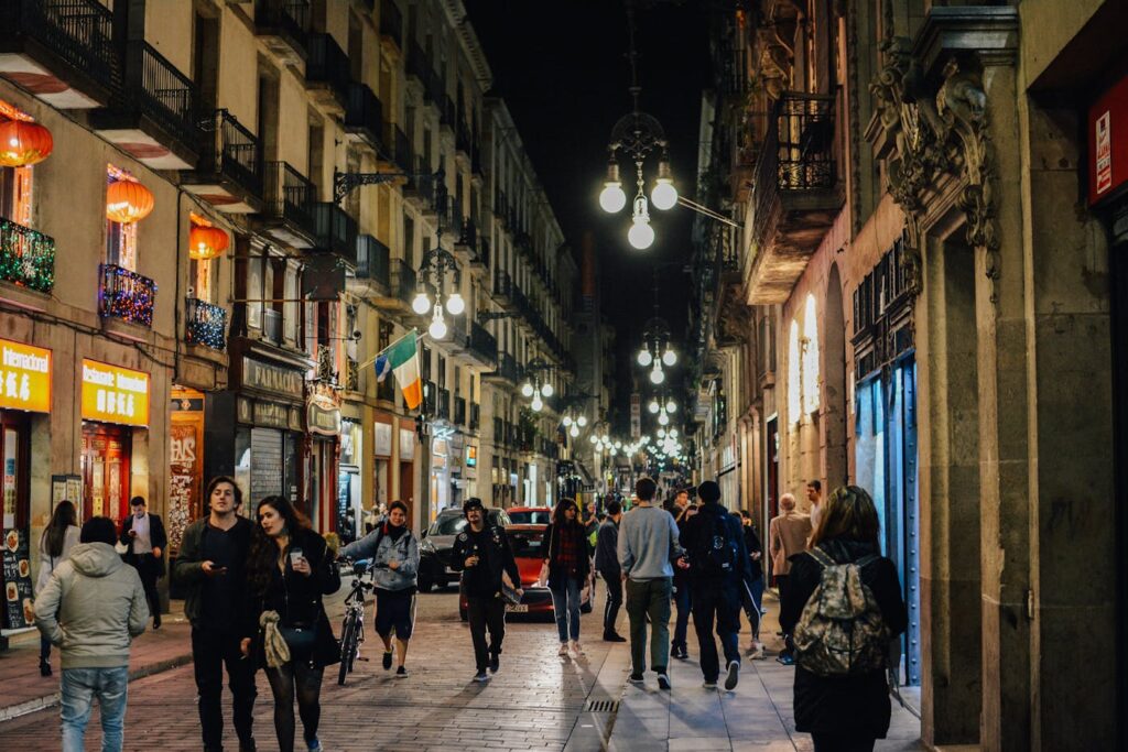 Vibrant nightlife in Barcelona's old town with people walking under street lamps.