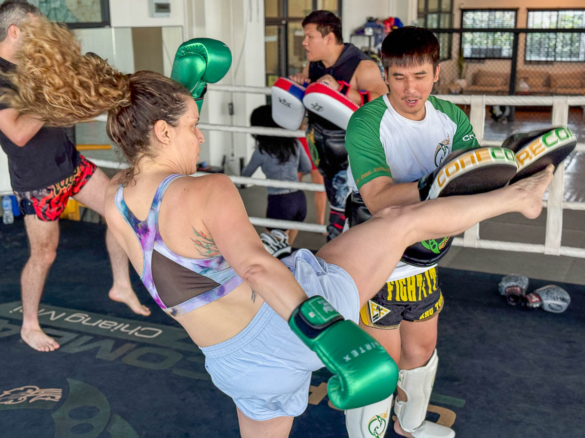 Nina kicking a pad her coach is holding.