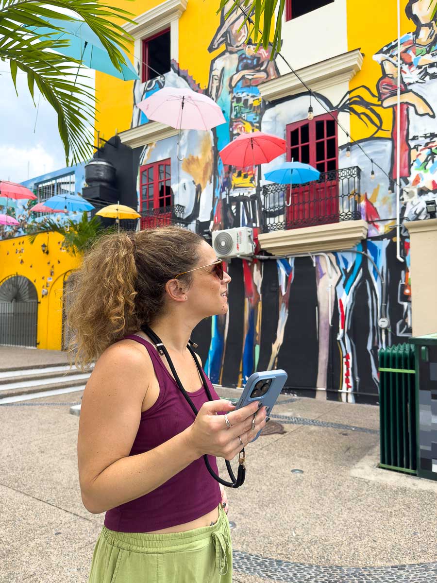 Nina on her phone on colorful street.