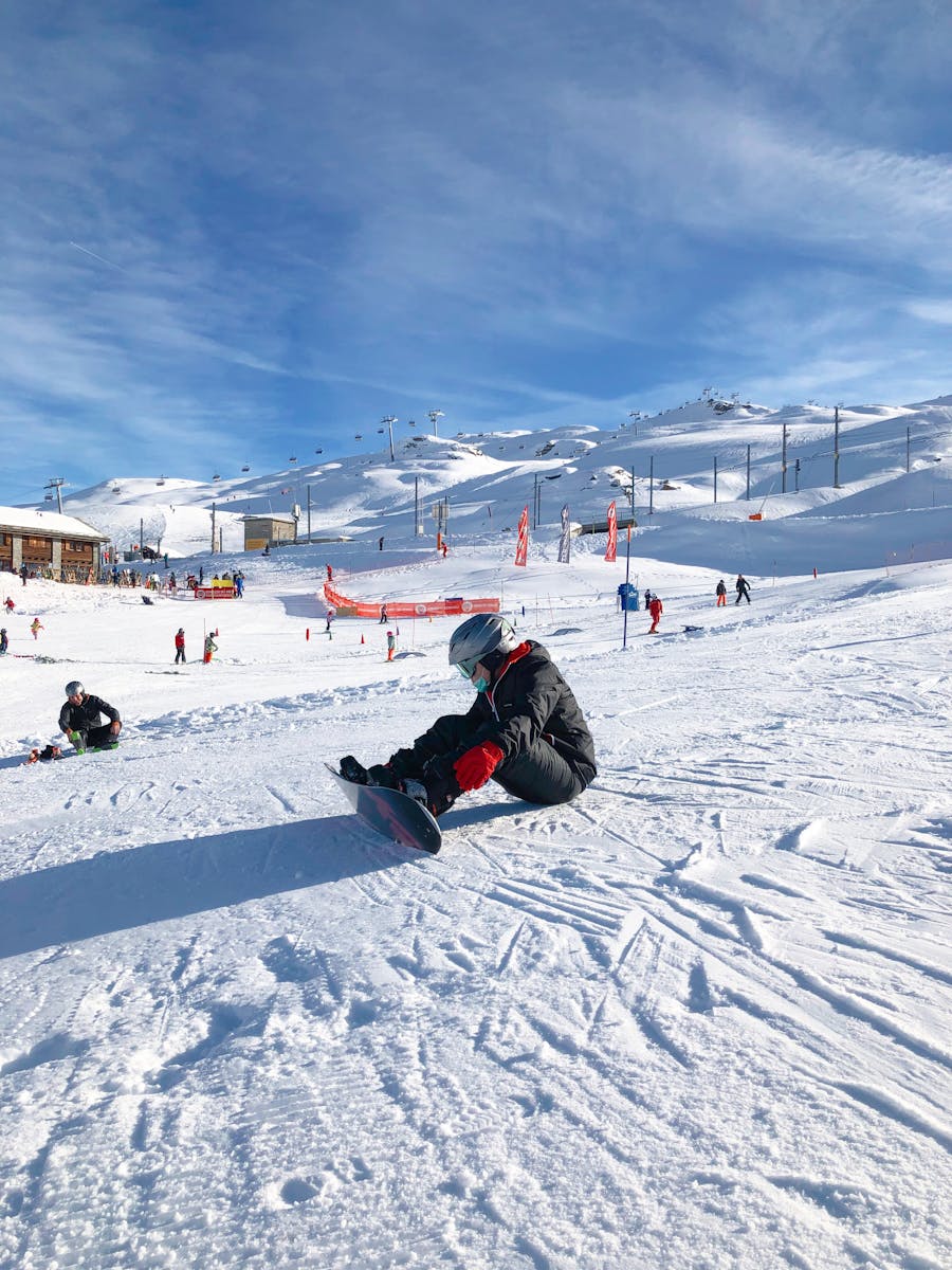 A snowboarder takes a break on a sunny winter day at a ski slope in Zermatt, Switzerland.