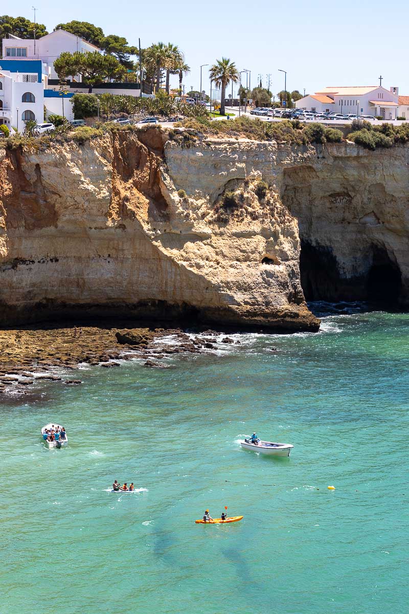 Kayakers in ocean with cliffs backing them.
