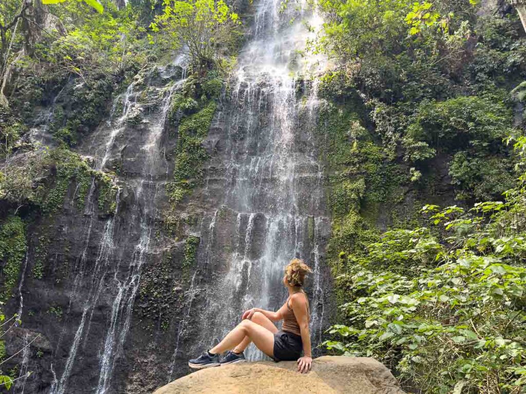 Nina sitting on a rock looking at one of the waterfalls on the 7 waterfalls hikes in El Salvador.