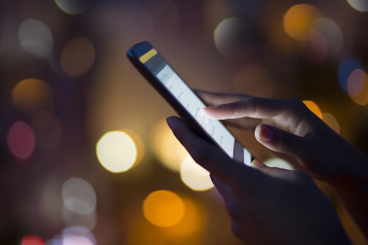 Woman using her mobile phone , city skyline night light background