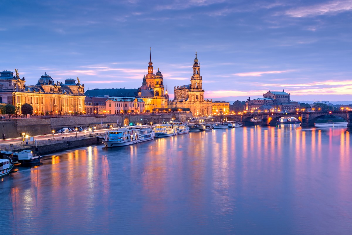 Dresden, Germany cityscape of cathdedrals over the Elbe River at dusk.