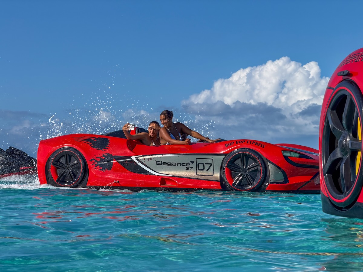Red jet car in water with two women taking a picture in it.