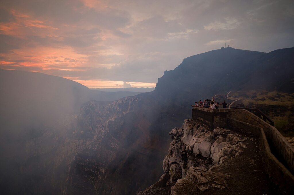 Tourists observe a volcanic crater at sunset
