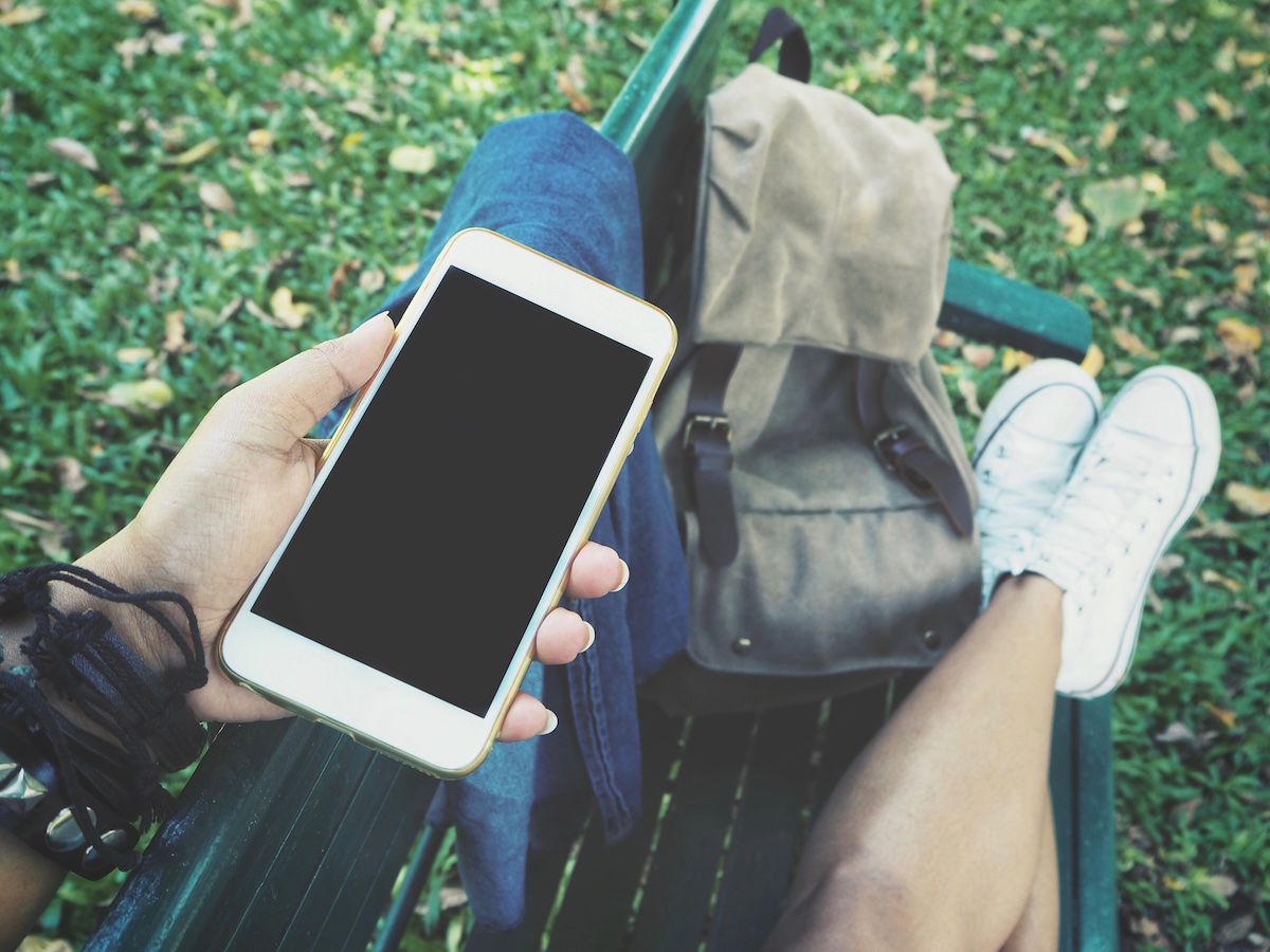 Woman using smart phone traveling with backpack