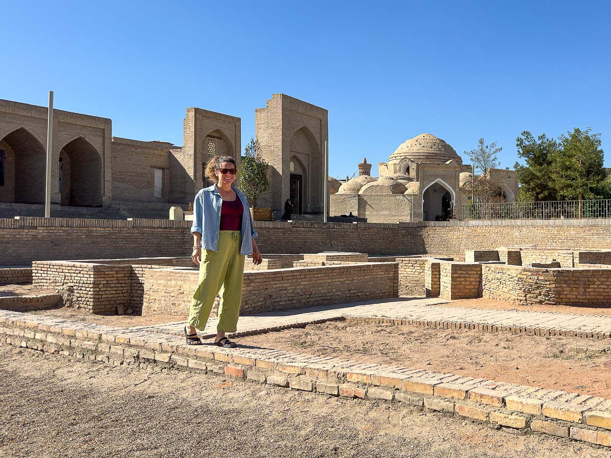 Nina walking past the archaeological excavations with domes behind in Bukhara, Uzbekistan