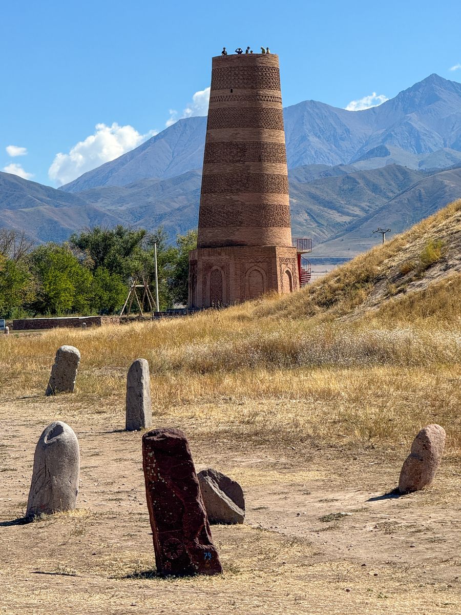 Burana Tower with balbal stones and mountains behind, Kyrgyzstan