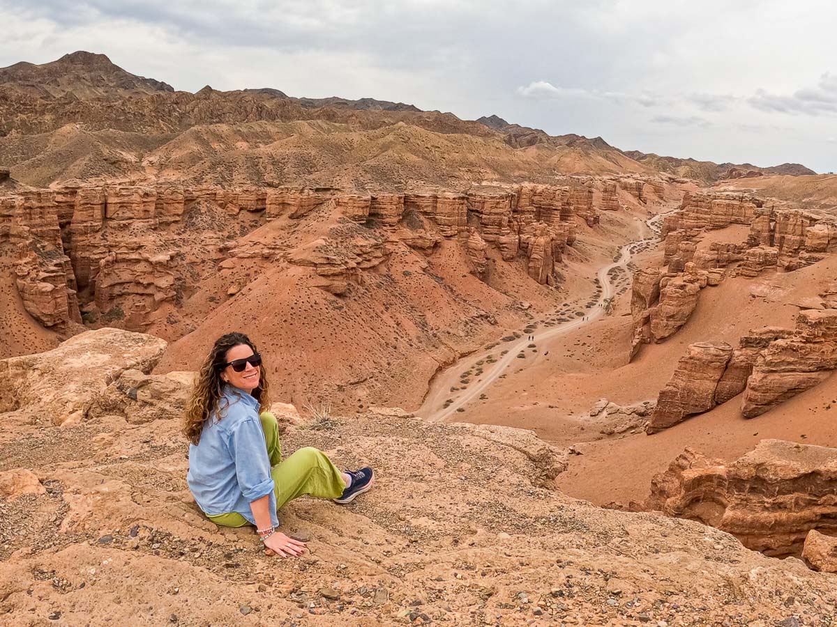 Nina sitting above the red rock walls of Charyn Canyon, Kazakhstan
