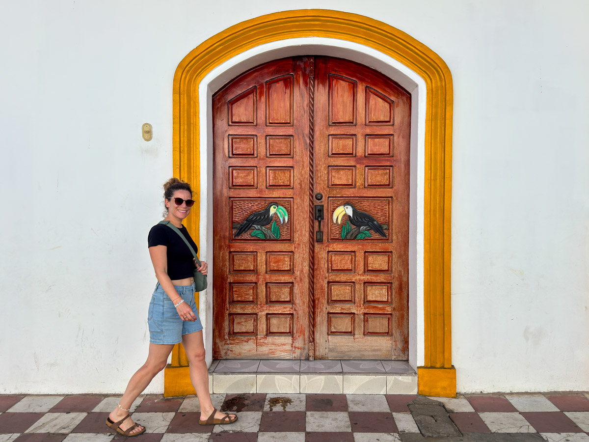 Nina walking past a colorful colonial doorway in Granada