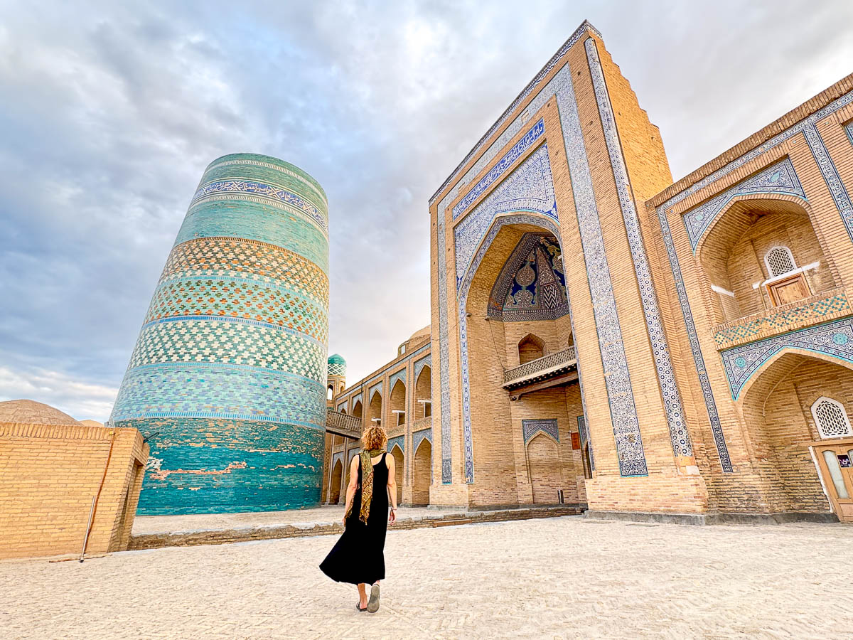 Nina by the blue tiled minaret in Khiva at golden hour, Uzbekistan