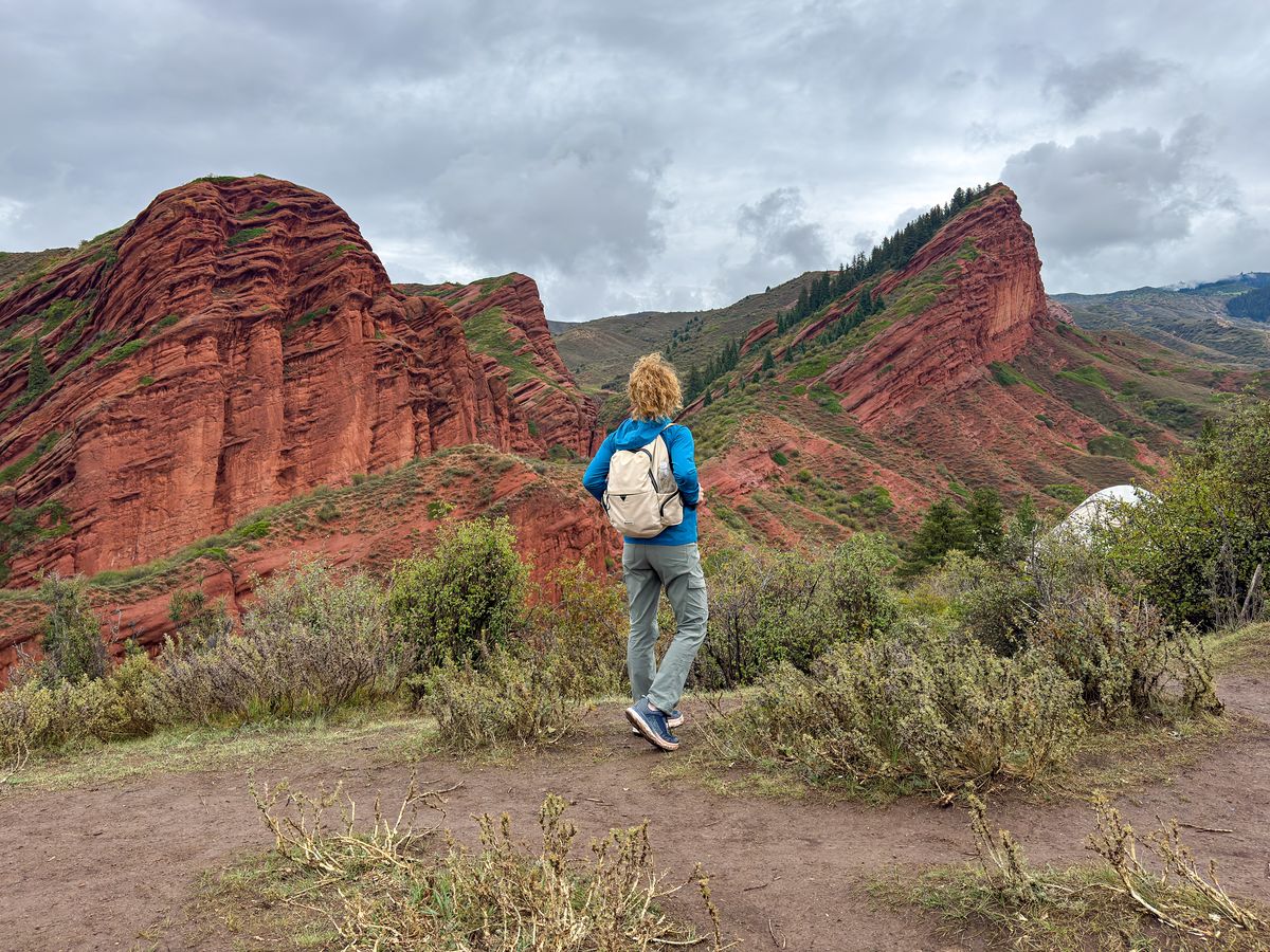 Nina hiking toward the red Seven Bulls rock cliffs in Jeti-Oguz, Kyrgyzstan