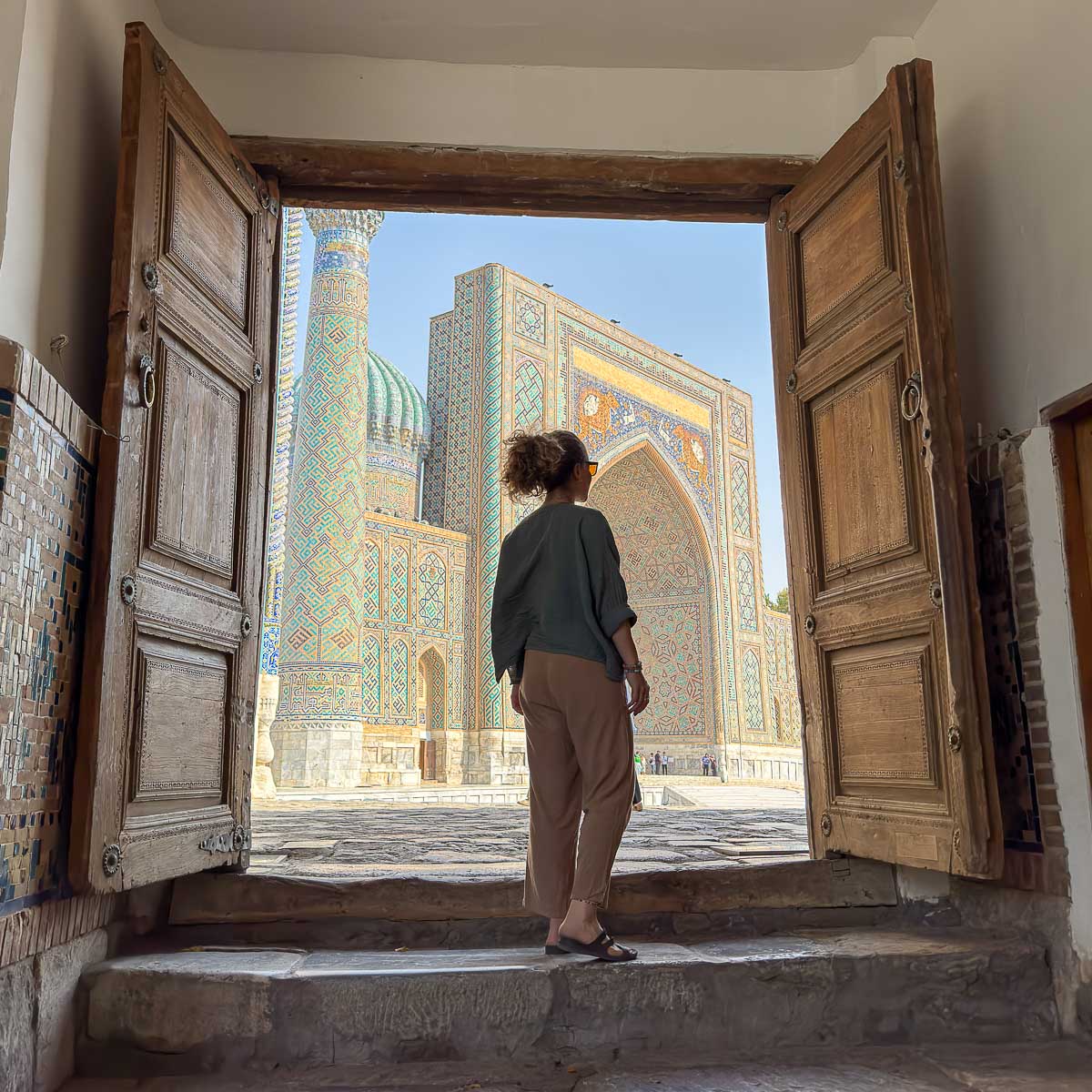 Nina standing in a tiled doorway at Registan Square in Samarkand, Uzbekistan