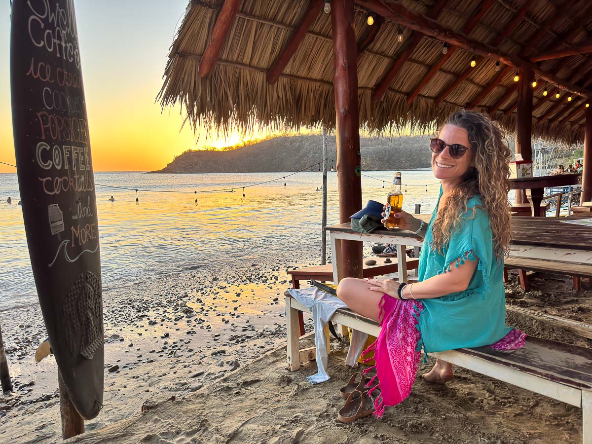 Nina with a beer at a beach restaurant on Playa Remanso
