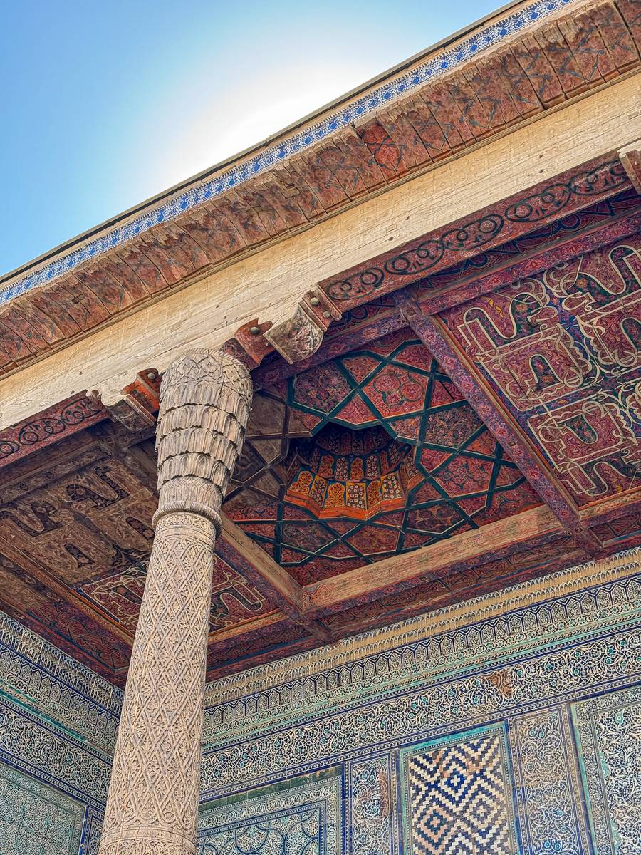 Carved wooden column and painted ceiling at Tosh Hovli Palace in Khiva, Uzbekistan